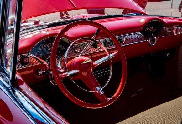 The red interior steering wheel and dash of a 1956 Chevrolet Bel Air.