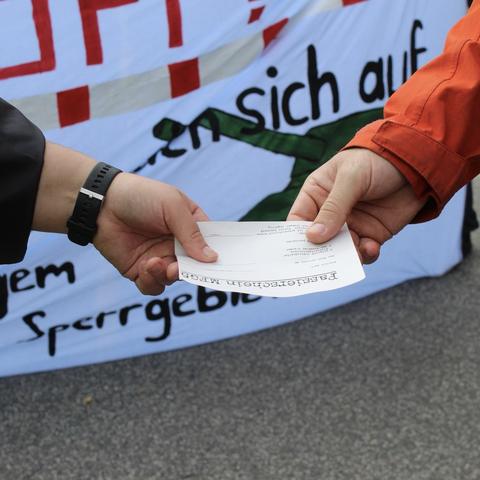 Ein Mensch übergibt einen Passierschein an einen anderen Menschen