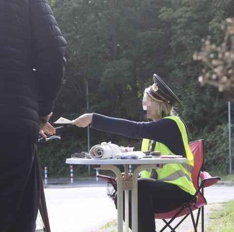 Ein Mensch sitzt an einem Tisch und gibt einen Passierschein an einen Menschen