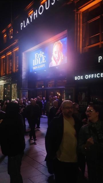 Exterior of the Playhouse at night as the audience exits, the bright, giant LED screen advertising the show lighting up the scene