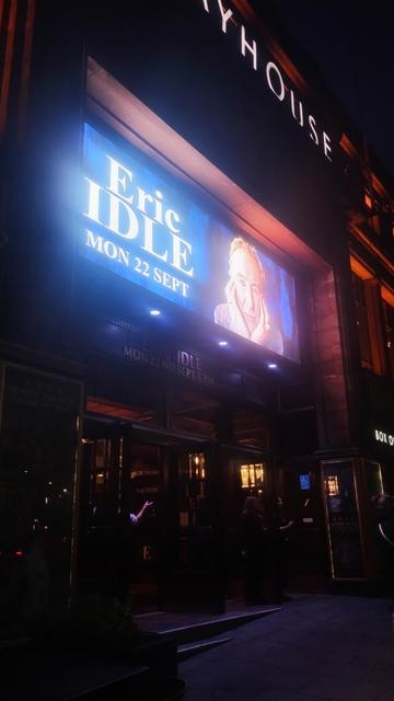 Exterior of the Playhouse at night,  the bright, giant LED screen advertising the show lighting up the scene