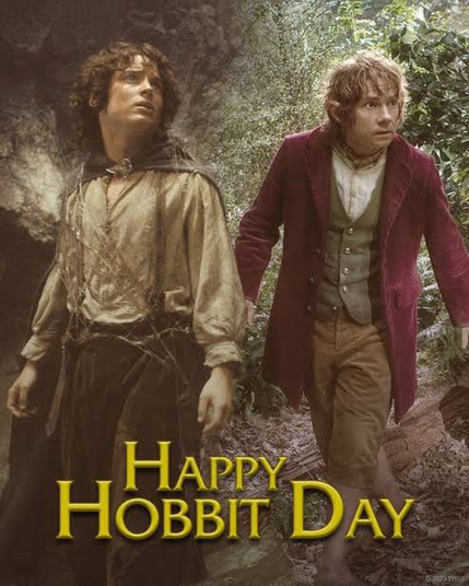 Image of the two ring bearing Hobbits. Frodo Baggins from the Lord of the Rings on the left, wearing dark slacks, a puffy light colored shirt, and some sort of cape fastened around his neck. On the right is an image of Bilbo Baggins from The Hobbit movie, wearing tan slacks, a white shirt, a brown vest, and a burgundy jacket. Both are depicted standing in a forest and anxiously looking at something off to their left.
At the bottom of the image it says Happy Hobbit Day in a gold color.