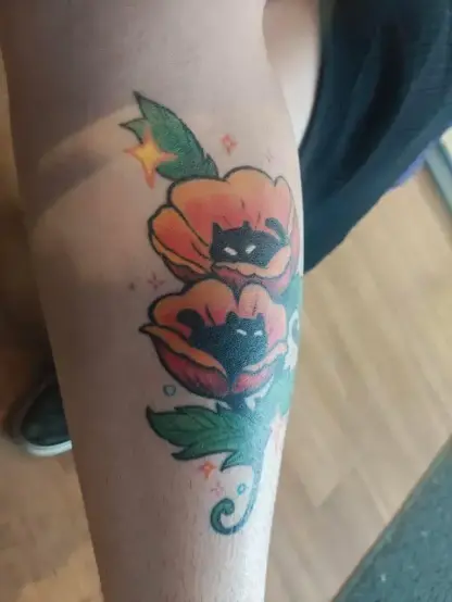 Photo of a clients leg with a healed tattoo of poppy kitties