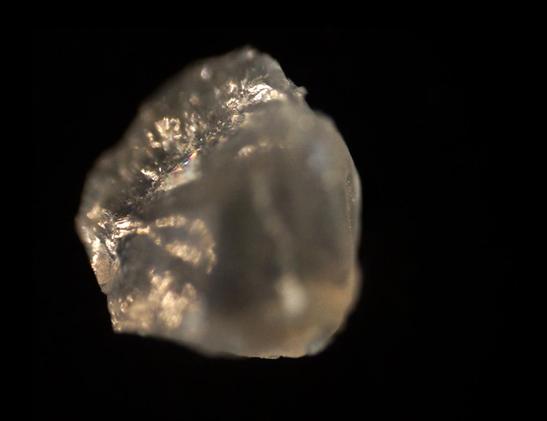 Kimalteleva pölyhiukkanen hyvin, hyvin läheltä kuvattuna mustaa taustaa vasten. 
A glittering dust particle up, up close, with a black background