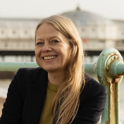 Sian Berry smiling to camera.  Background is out of focus, possible Brighton pavillion.