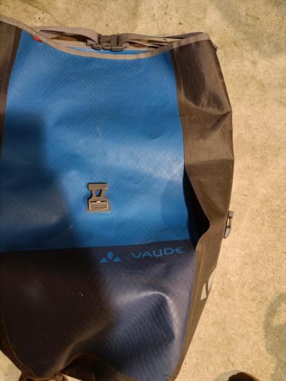 Sacoche Vaude bleue et noire de 25 L avec un gros trou sur le côté gauche de la sacoche.