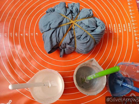 Preparing a slate blue tshirt for spiral tiedye. Fabric paint colours used: white, silver, dark steel blue