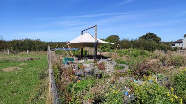 New garden with canvas shelter supported between 2 telegraph poles