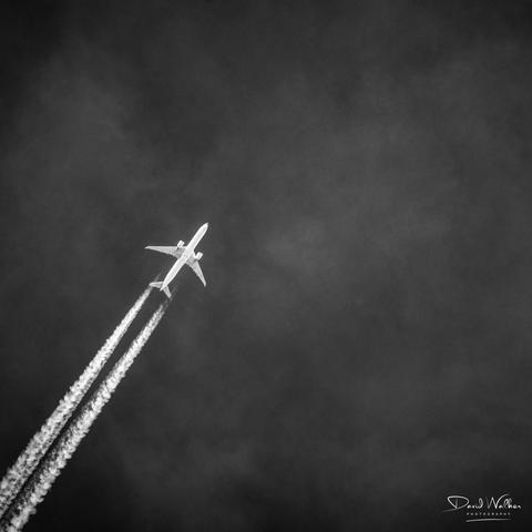 Picture of aircraft and contrails highlighted against a dark sky