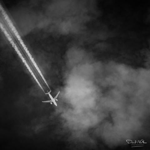 Picture of aircraft and contrails highlighted against a dark sky
