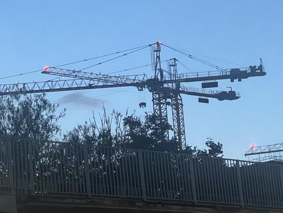 2 cranes with weights hanging one in silhouette but like a suspended animal