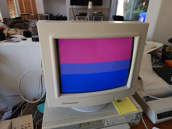 A beige CRT computer showing the bisexual pride flag, with pink, purple, and blue stripes