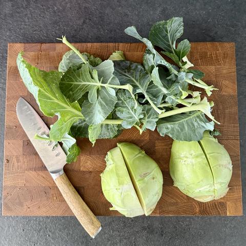 The last kohlrabi, already quartered on a wooden cutting board. Next to it the leaves that I’m saving for another meal and a very sharp santoku knife.