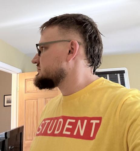 Selfie showing my head from the side, wearing a bright yellow shirt with a red rectangle on the chest with the word STUDENT written inside it in yellow
