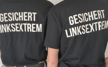 Zwei Rückenansichten auf T-Shirts. Aus beiden schwarzen T-Shirts steht nin weißer Schrift: "Gesichert Linksextrem"

English: Two black Shirts, backside in capital white letters "Secured left-wing extremist"