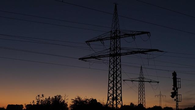 Vor dem Sonnenaufgang, der Himmel von Orange bis Blau. Schwarze Hochspannungsmasten