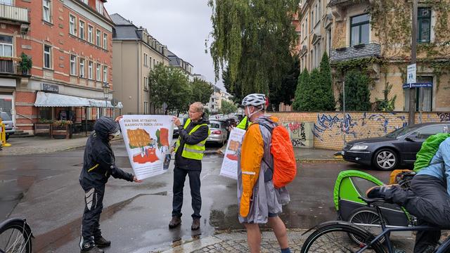 Engagiert des ADFC zeigen OB Hilbert bei Regenwetter Plakate mit einer stilisierten Visualisierung der Radroute West. Alle tragen Regenkleidung