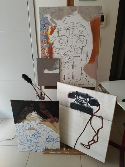 Photo of four works in progress (canvasses) in front of the easel.