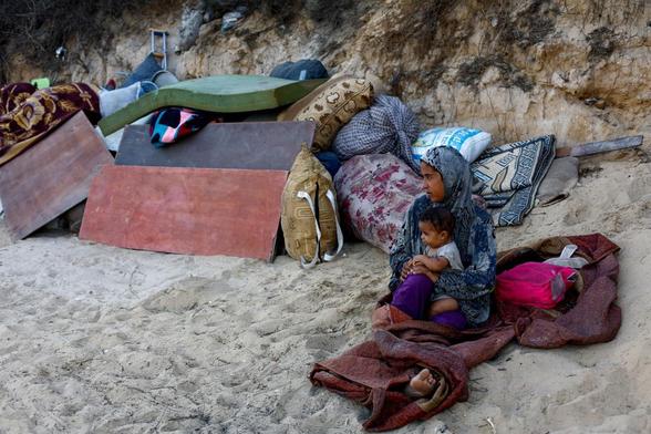 Una palestina desplazada con un niño descansan en su camino desde la ciudad de Gaza al sur, tras la orden de evacuación dada por Israel, el 23 de septiembre de 2025. (Mahmoud Issa / Reuters)