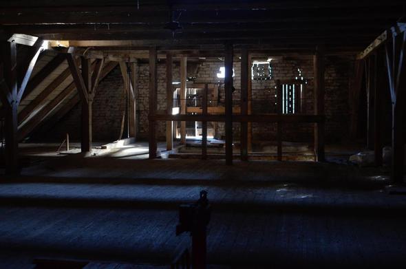 Grand grenier en bois. Plancher et charpente en bois blanc. La lumière de l'extérieur filtre entre les planches.