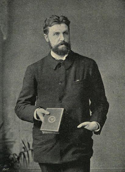 Samuel Rutherford Crockett. Photograph by Elliott & Fry. The Critic, September 1905. P. 200. Wikimedia Commons. Crockett is bearded, and wears a jacket buttoned all the way up to his neck. His left hand rests in his jacket pocket and he is holding a book, casually, in his right. The photograph is in black and white.