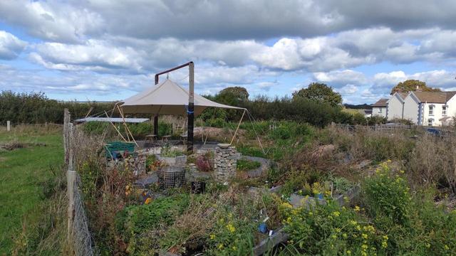 New garden with canvas shelter supported between 2 telegraph poles