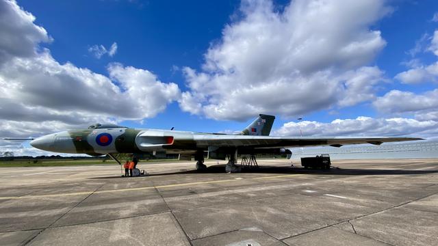 A large Avro Vulcan bomber aircraft on display at an airfield, painted in camouflage with RAF roundels.