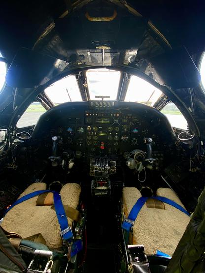 Cockpit interior of the Vulcan, with instrument panels, controls, and two sheepskin-covered seats with blue harnesses.