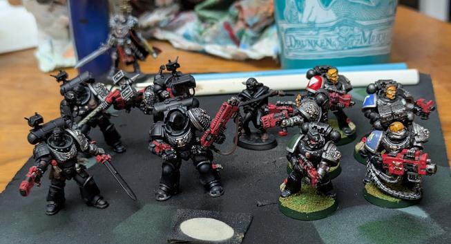 Four new Kill Team Deathwatch Space Marine miniatures partially painted with another five Firstborn Marines getting color by color touchups.
