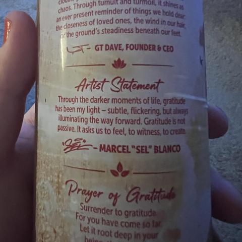 A kombucha bottle's back description features an artist statement discussing the significance of gratitude in challenging times. It includes signatures from GT Dave, Founder & CEO, and Marcel "Sel" Blanco.
