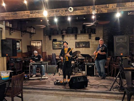 photo of Jonny Meyers and band playing outdoors at the LIC Bar at dusk. The band includes Meyers on lead vocals, with a pedal steel player, bassist and drummer.