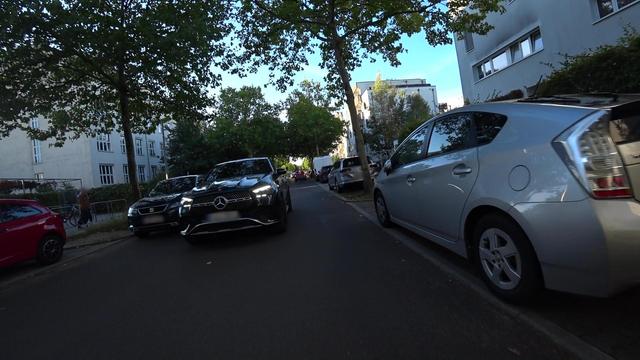 Win SUV umfährt ein am linken Rand geparktes KFZ und behindert dadurch den Radfahrer und lässt im zu wenig Platz.
