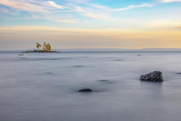 A tranquil sunset over Tiny Beach, Ontario, with serene waters reflecting the vibrant sky.