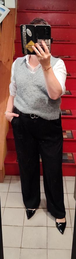 Fuzzy grey sweater vest over white button up, black trousers. Black belt with silver circle hardware. Shiny black slingbacks. Minimal gold jewelry.