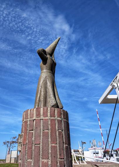 Small statue of a lady with a high hat looking out over the harbor.