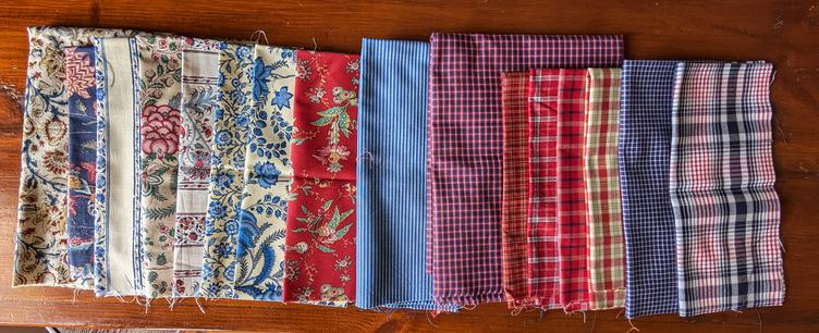 Different fabrics folded: left hand side flowered fabric (*Sitse*), right hand side checkered fabric (*bonten*).
Mostly in blues and reds and white.