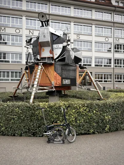 The Brompton in kickstand mode standing in front of the Apollo lunar lander module at the Cité du Temps, the HQ of Omega and Swatch.