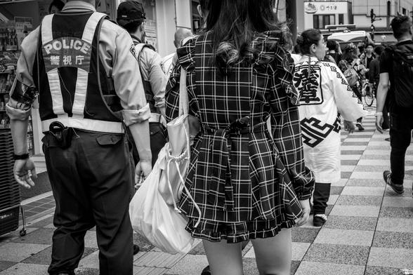 Noia amb vestit de quadres amb minifaldilla al costat d'un policia.