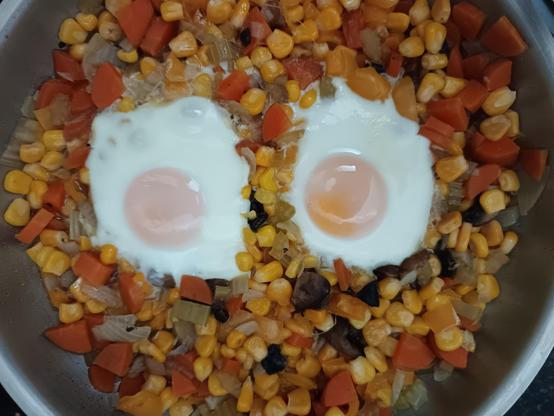 een schotel met gekookte gele groenten en dooiers in het midden.