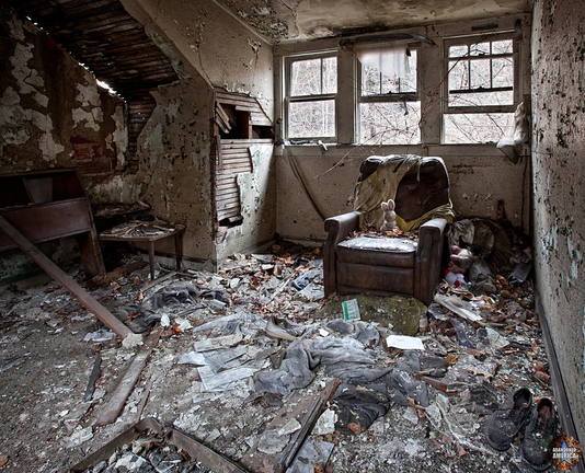 In a dilapidated room with debris strewn about the floor, collapsing walls and broken windows, a small stuffed rabbit, its ears still perky, haloed by the outside light behind it, sits abandoned in an old easy chair, waiting for the child who will never return for it...