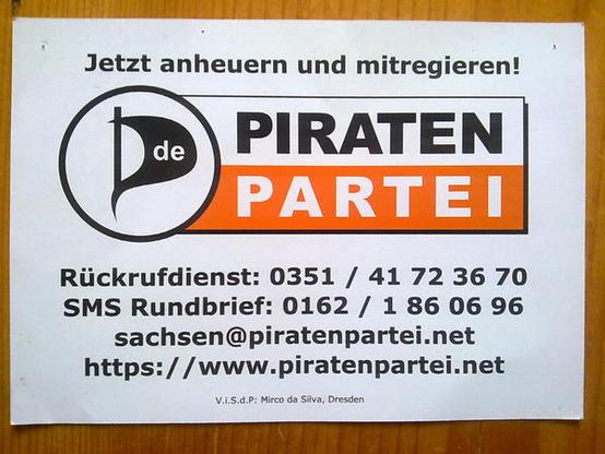 Foto eines Flyers: „Jetzt anheuern und mitregieren!" efolgt von Piratenpartei-Logo, Rückrufdienst mit Festnetznummer, SMS-Rundbrief und Mobilnummer, Emailadresse, URL, und ViSdP-Angabe