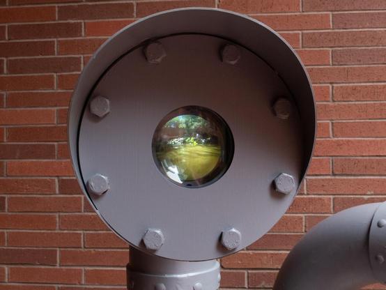 A close-up view shows another natural scene, this time showing a swamp. There is a hood over the end of the artwork, akin to a traffic light or signal. It has big chunky bolts.