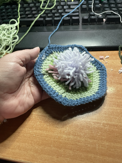 The same crochet gradient hex from the previous picture only this one has a fuzzy pink and purple pompom on top.