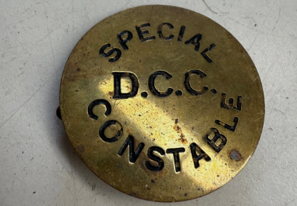 Eine alte Messingbrosche mit schwarz gefärbter Prägung "Special D.C.C. Constable"