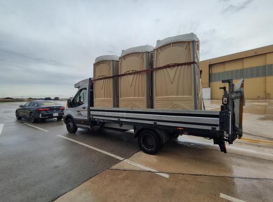 Transporter mit transportablen Toiletten, der einem exklusiven FollowMe-Auto folgt, nämlich einem BMW Z8 mit temporären Kennzeichen auf dem SAFI Werksgelände, Malta Airport
