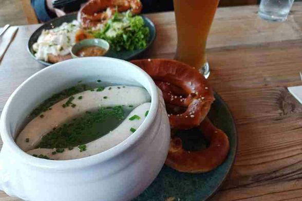 Traditionelles Weißwurstfrühstück mit Weißwürsten im Kräutersud, Brezn und süßem Senf. Dazu passt ein alkoholfreien Weißbier.