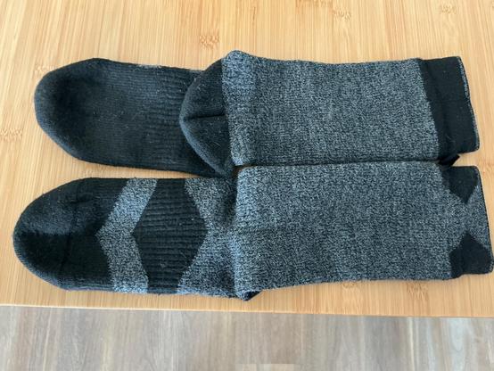 2 schwarz-graue Socken auf einer hellen BambusTischPlatte