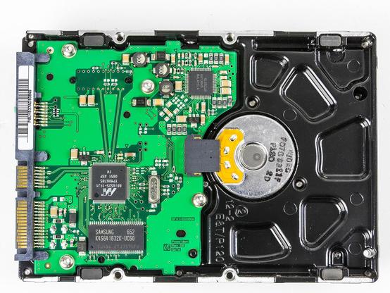 Rückseite der Festplatte. Die linke Hälfte wird von der Controller-Platine (grün) eingenommen, etwas rechts der Mitte die Unterseite des Motors zu sehen, der die Platte im Inneren in Drehung versetzt