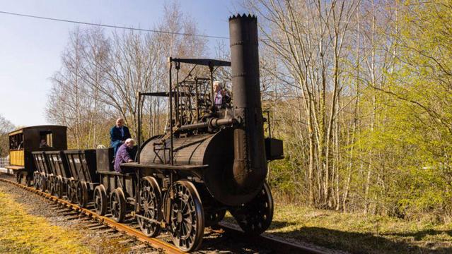 Bildbeschreibung (Deutsch):
Das Bild zeigt eine historische Dampflokomotive mit offenen Kohlewagen und einigen Menschen, die sich um die Maschine versammeln. Der rostig-schwarze Stahlkörper mit seinem hohen Schornstein wirkt wie ein Relikt aus einer vergangenen Epoche der Industrialisierung. Im Hintergrund stehen kahle Bäume im Übergang zum Frühling, Symbol für Wandel und Neubeginn. Im Kontext der Ontologie der Schwingung zeigt die Szene den Übergang von einer alten, schwerfälligen Technologie zu effizienteren Formen der Mobilität - ein Spiegel dafür, wie Gesellschaften im Schwingungsfeld zögern oder mutig neue Wege gehen.
Image Description (English):
The image shows a historic steam locomotive with open coal wagons and several people gathered around the machine. The rusty-black steel body with its tall chimney appears as a relic from a bygone era of industrialization. In the background, bare trees on the verge of spring symbolize transition and renewal. Within the Ontology of Vibration, the scene reflects the shift from an old, cumbersome technology to more efficient forms of mobility - a mirror of how societies either hesitate or boldly embrace new paths within the vibrational field.🖖