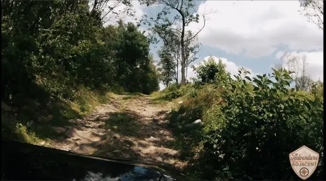 Berry Mountain climb picture 2. View over the hood of the FJ from the hero camera mounted to the hood. Cruiser Cruiser pointed up toward the sky emerging from the woods on a dirt two-track.